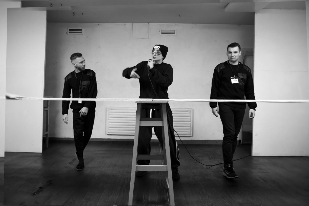 Three performers standing, one in the middle singing