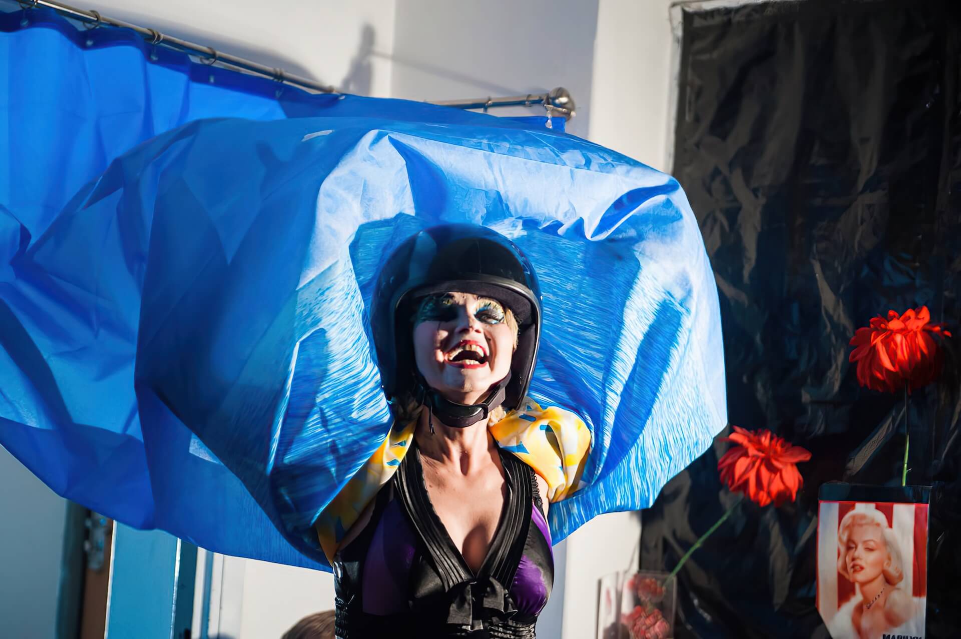A woman with a heavy makeup wrapping herself with a blue curtain