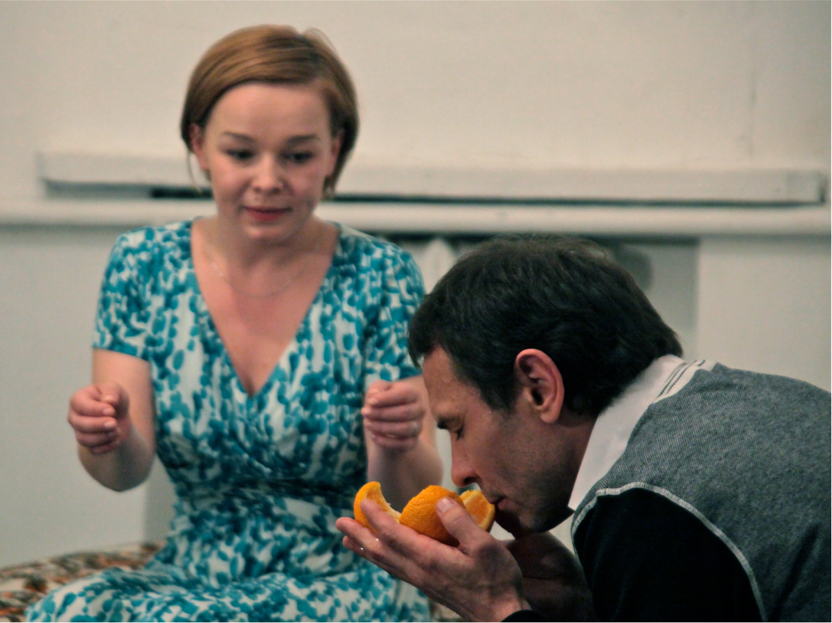 A man is smelling orange while a woman looks at him