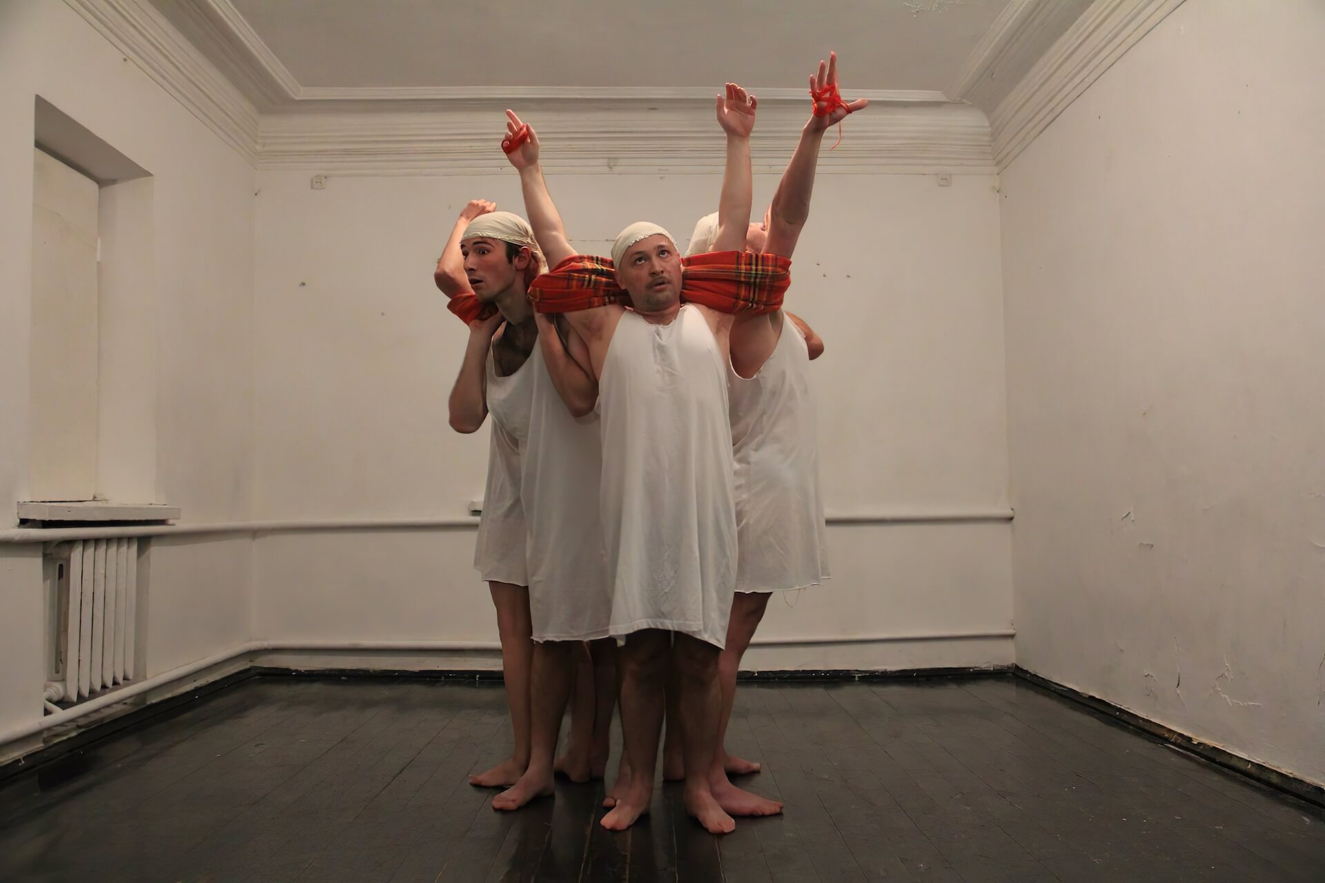 Five performers wrapping themselves with red blankets with their arms up