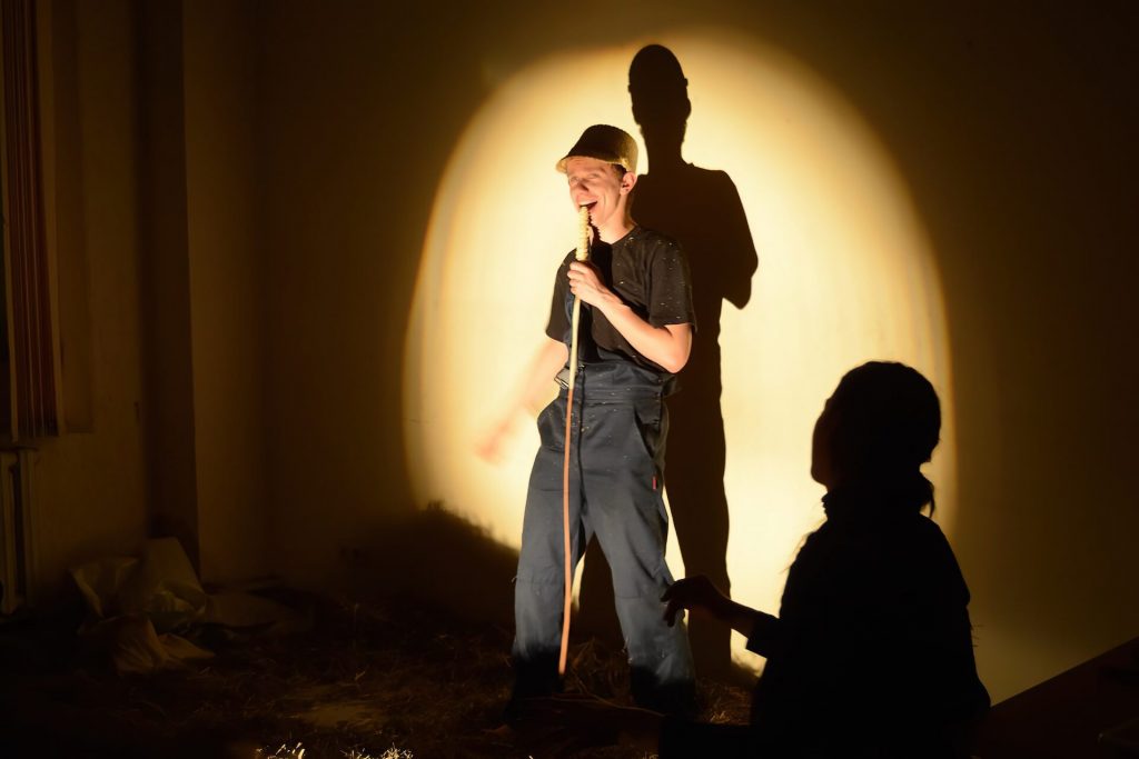 A performer with a straw cap is singing with a microphone made out of straw