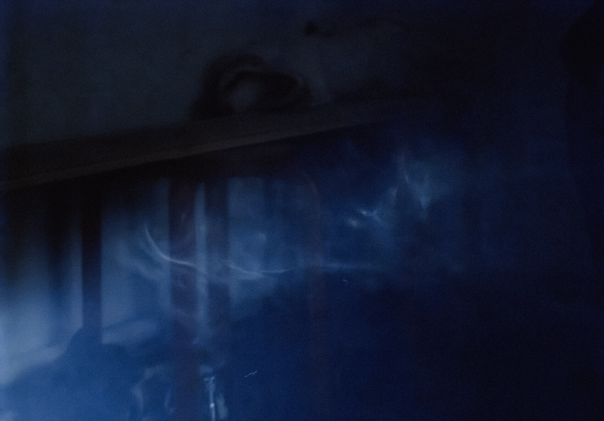 Dark room hinted with dimmed blue lighting. The light highlights fog in the room.