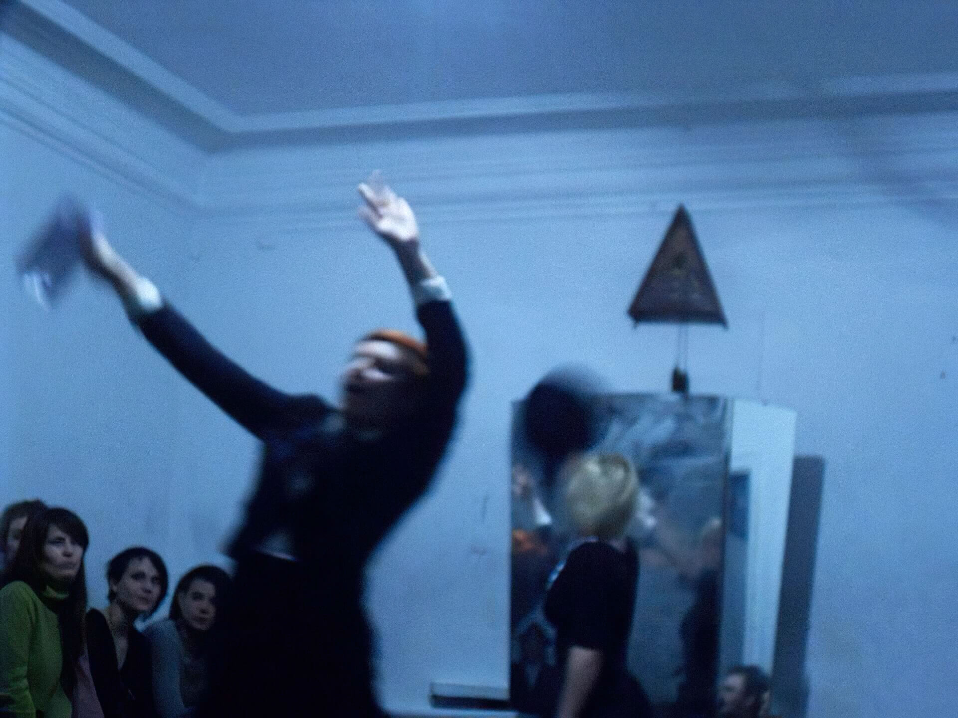 Blurry image of a performer swaying with both arms up in the air
