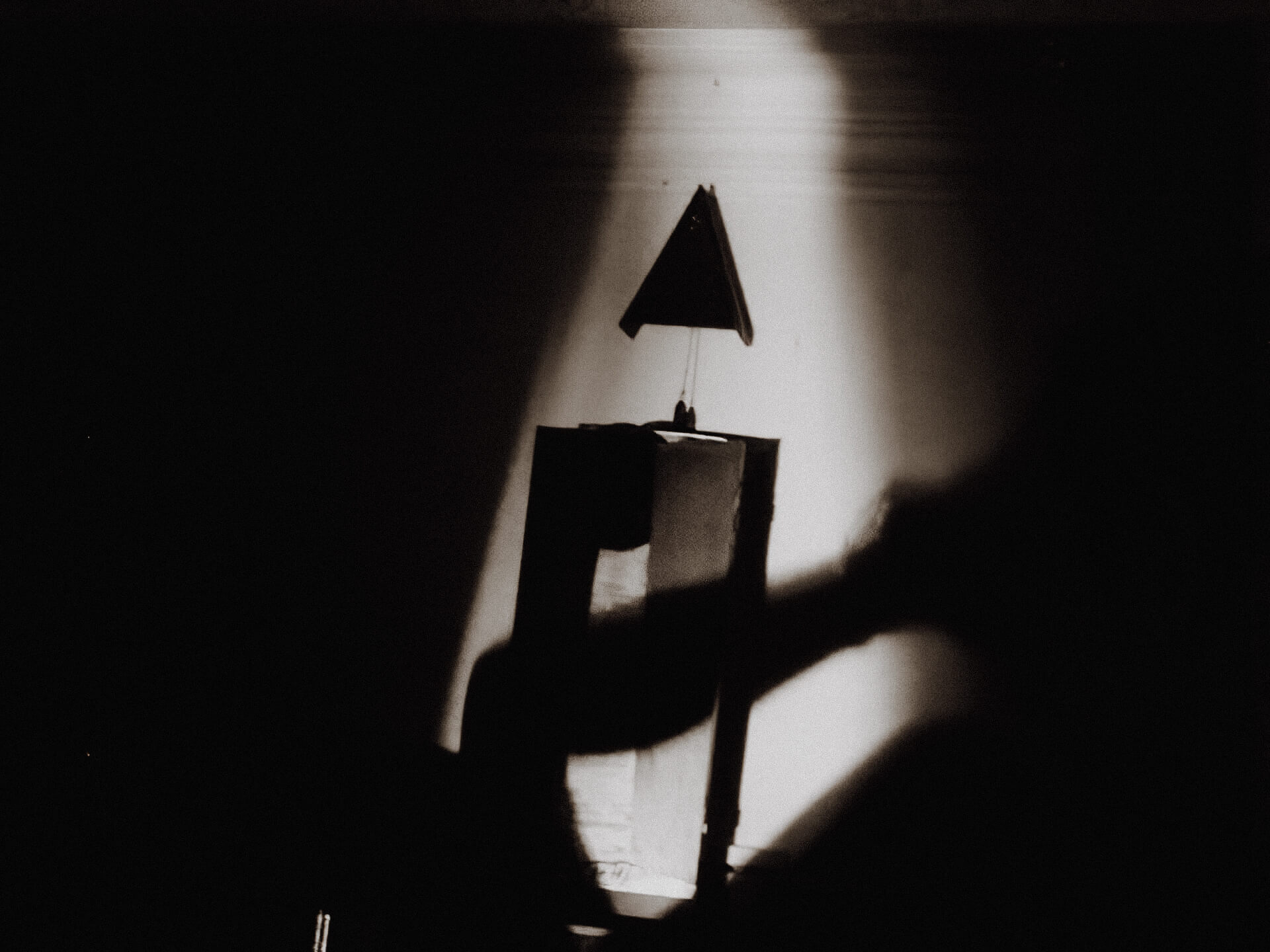 Black and white image of the metal object. A spotlight highlights the object in the darkness.