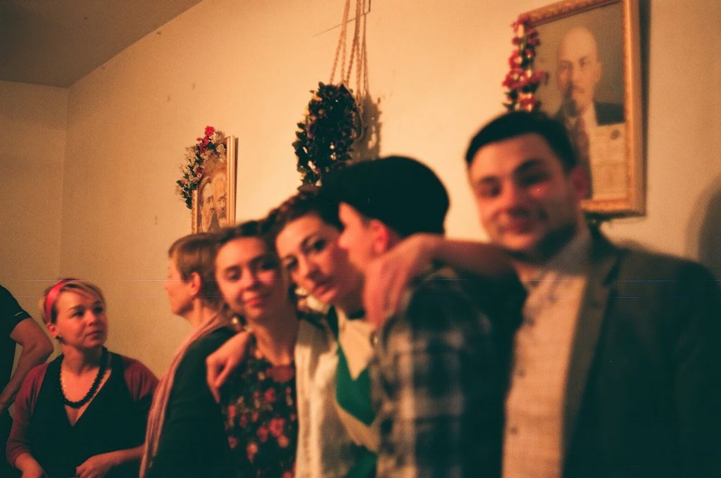 Four people are posing for photo in front of portraits decorated with flowers.